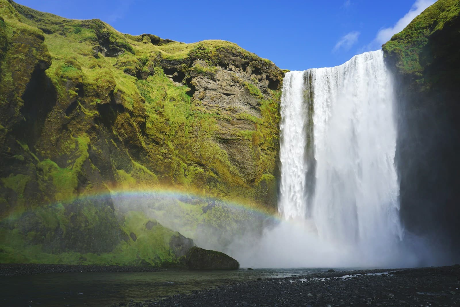 Skógafoss waterfall surrounded by green cliffs in Iceland