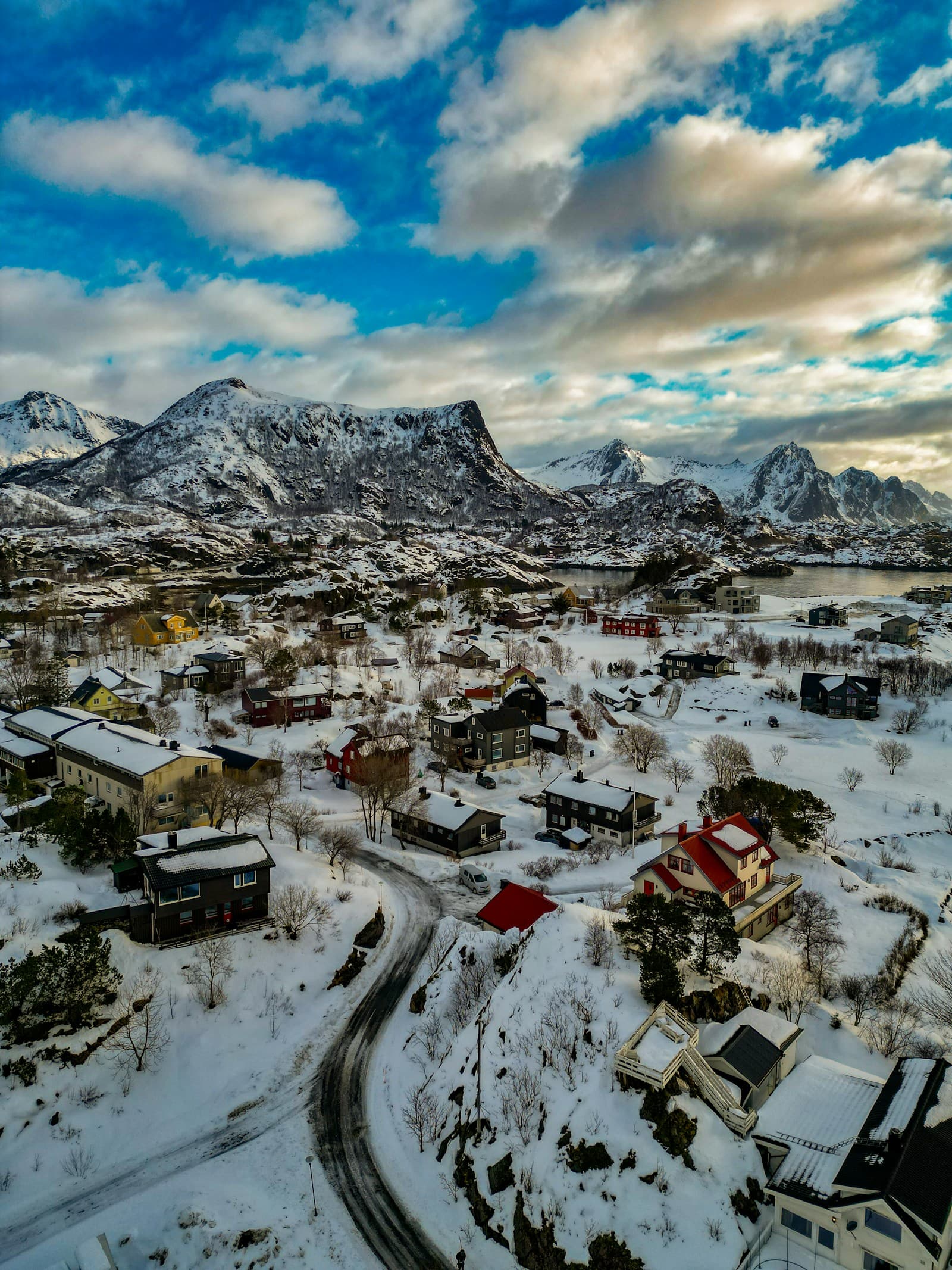 An aerial view of a fishing village beside the water and snowy mountains in Lofoten, Norway